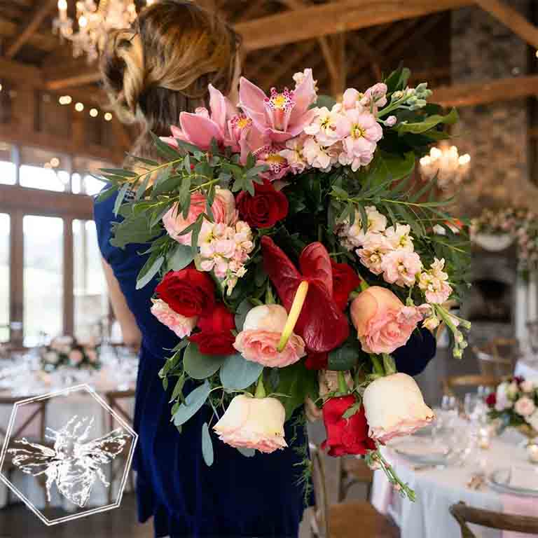 Person holding a large, colorful bouquet of flowers in an elegant indoor setting. Luxurious bouquet of hand tied fresh cut florals for any occasion