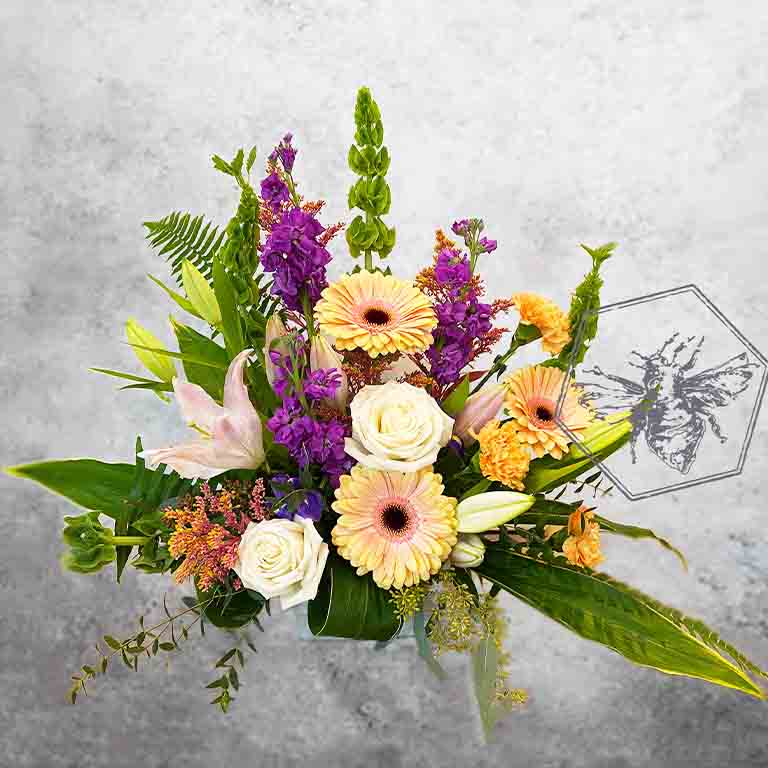 Large modern memorial flower arrangement and focal piece for service tables or church fronts, featuring a personalized, premium mix of colorful and white blossoms.