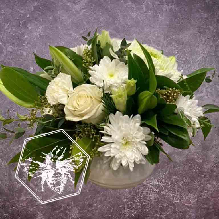 Compact arrangement  of white flowers with green leaves on a gray background