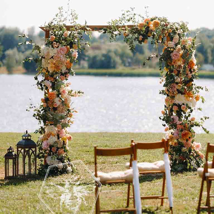 Pastel wedding floral arch outdoors with lake in the background
