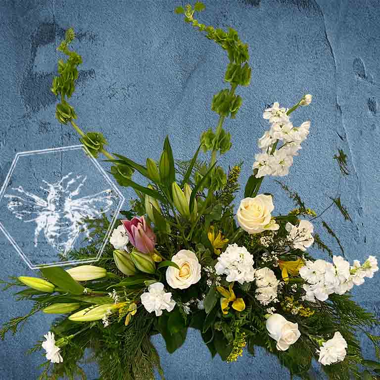 Large modern memorial flower arrangement and focal piece for service tables or church fronts, featuring a personalized, premium mix of colorful and white blossoms.