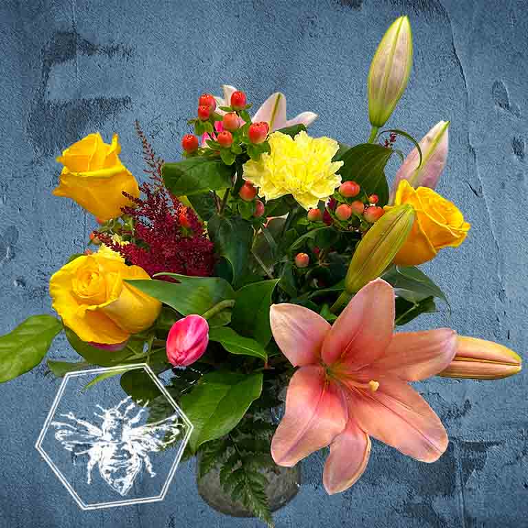 Bouquet of flowers with yellow roses, pink lilies, and green leaves on a textured blue background.