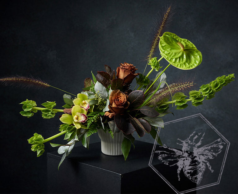 Modern arranged flowers with anthurium, roses fern, pussy willows and orchids with complimentary greenery in a ceramic pot