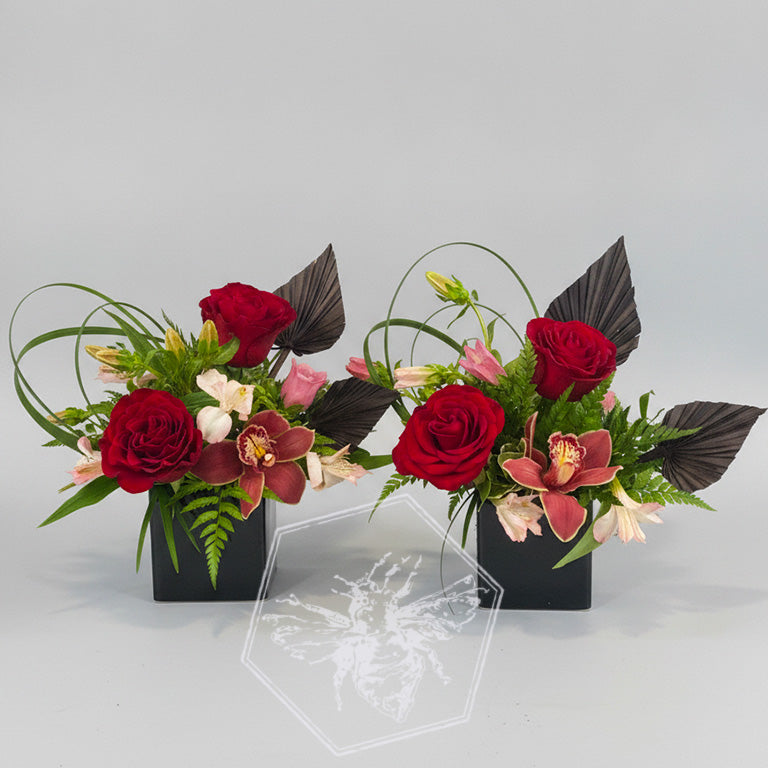 Romantic roses greenery, button mums and giant orchids nestled in lily grass accents in a white ceramic pot