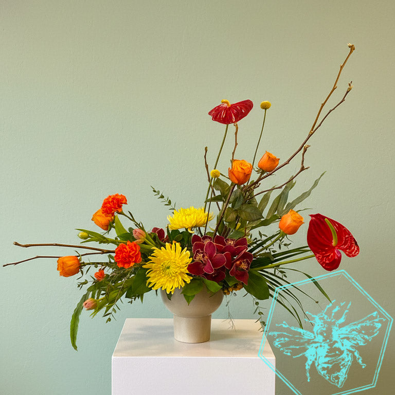Modern arranged flowers with anthurium, roses fern, pussy willows and orchids with complimentary greenery in a ceramic pot