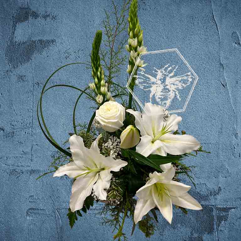 Traditional sympathy floral arrangement of white and pastel flowers in a glass vase accented by fresh tasteful blooms and complimentary greenery.
