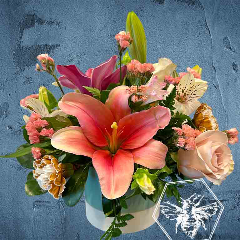 Compact arrangement of flowers with pink lilies and roses on a textured blue background in ceramic pot
