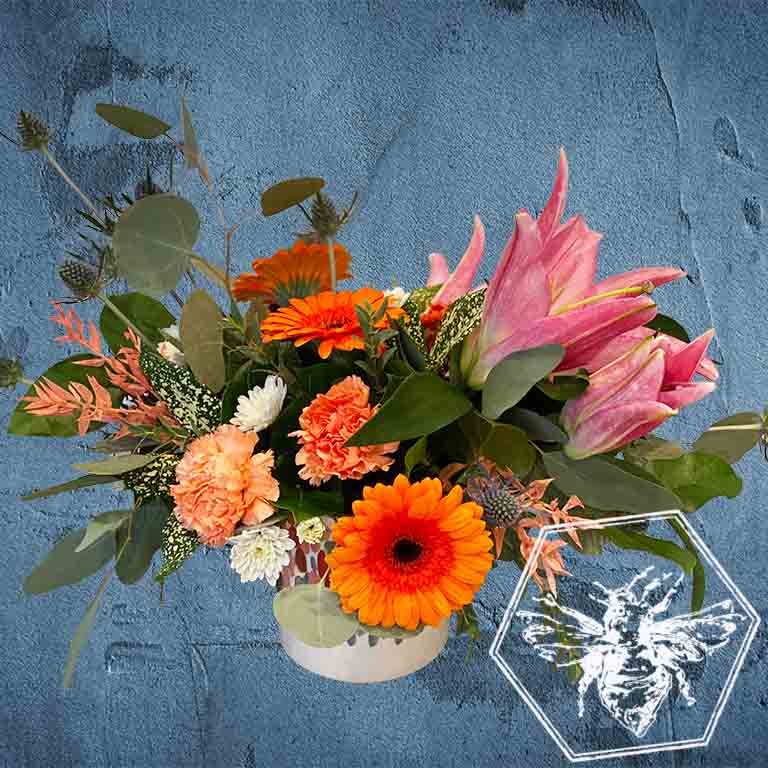 Lilies and Gerber daisies arranged in a decorative ceramic pot 