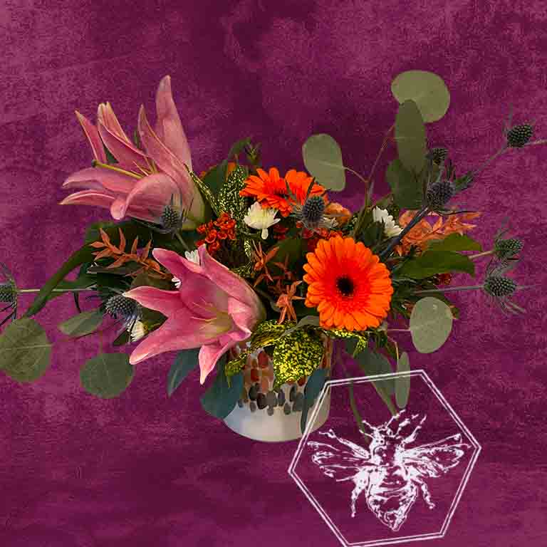 Stargazer lilies and Gerber daisies arranged in a ceramic pot
