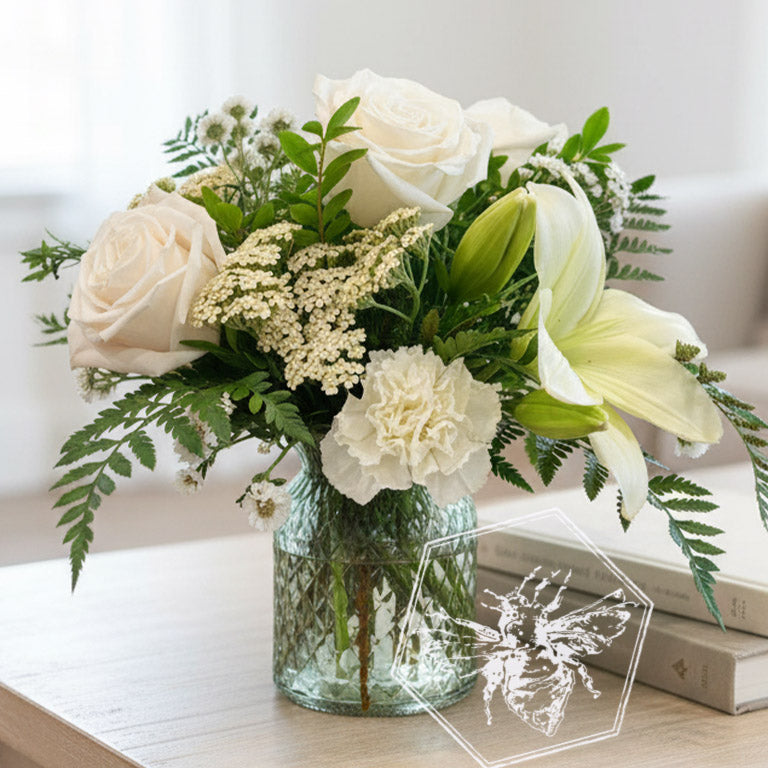 A traditional vase featuring white roses, lilies and reverent greens