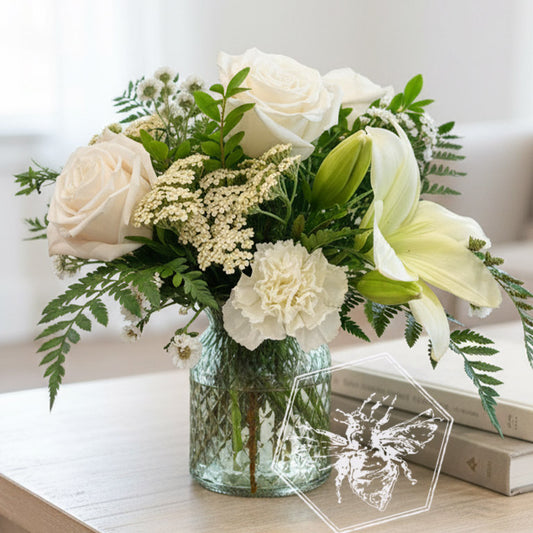 A traditional vase featuring white roses, lilies and reverent greens