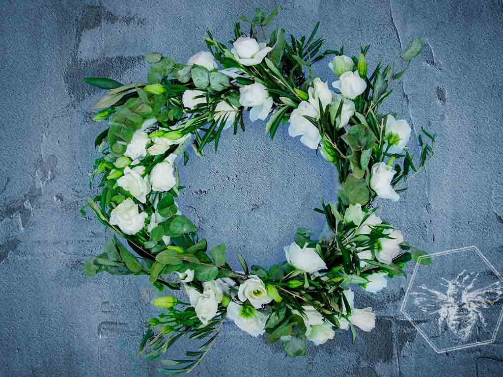 Floral wreath with white flowers and green leaves on a textured blue background