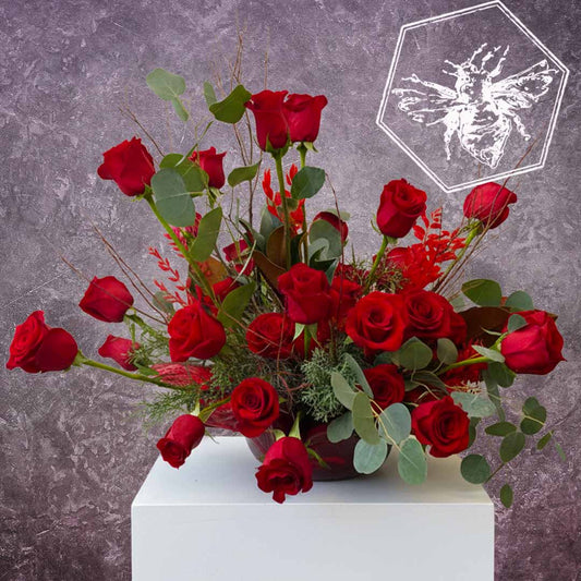 A modern arrangement of fresh cut roses with eucalyptus, Spanish moss, and complimentary greenery.  
