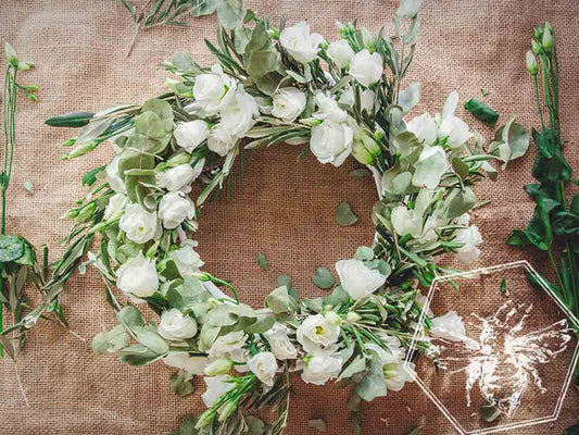 Floral wreath made of white flowers and greenery on a textured brown background