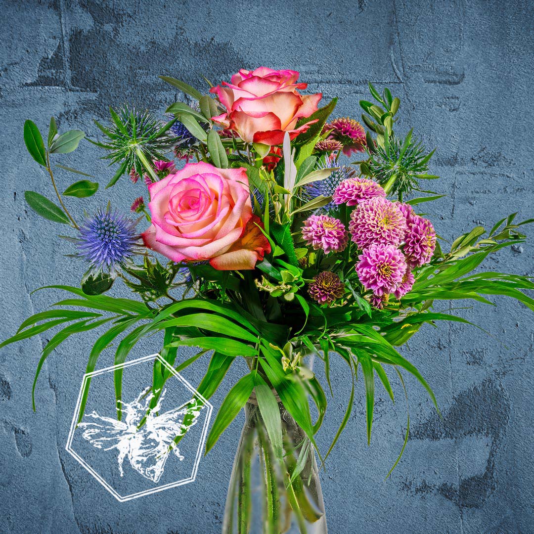 Bouquet of roses and greenery in a clear vase on a textured blue background