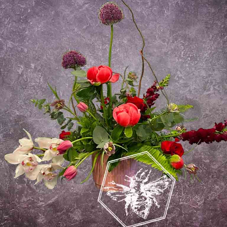 Modern seasonal flower arrangement with elevated feel and luxurious artisanal tone creatively and carefully crafted from the finest flowers and textures representing the season of the year featuring peonies, allium, mini cymbidium orchids, tulips and twig