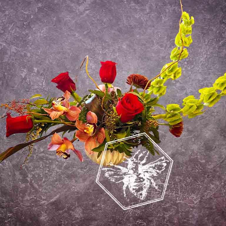 All of the colors of love wrapped up in modern luxury fresh floral creative brilliance featuring red roses, pink variegated giant orchids and Bells of Ireland