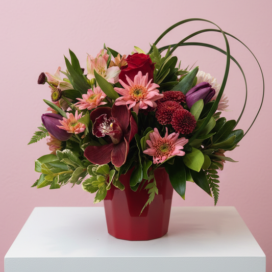 All of the colors of love wrapped up in modern luxury fresh floral creative brilliance featuring red roses and maroon giant orchids and deep tones of late blooming tulips