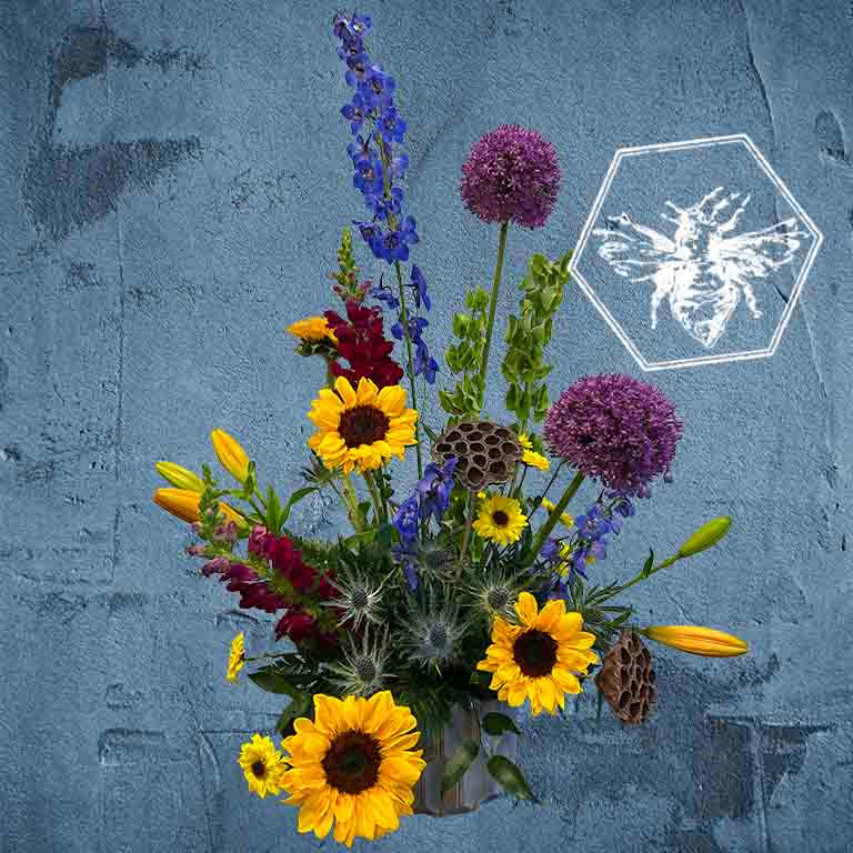 Luxurious modern arranged sunflowers  featuring lotus pods, lilies, allium, blue delphinium and bell of Ireland