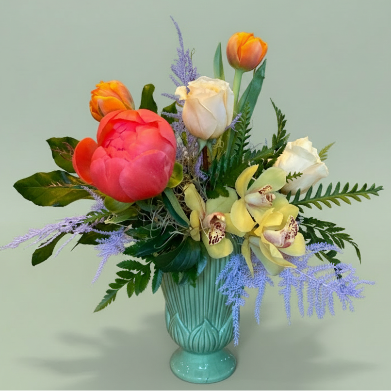 Colorful Peonies roses and orchids flower arrangement in a teal vase on a light green background