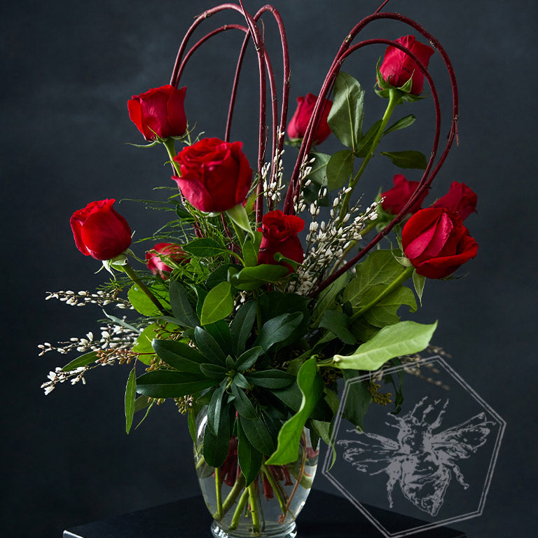 Black roses in a vase with a red heart-shaped watercolor design on a gray background.