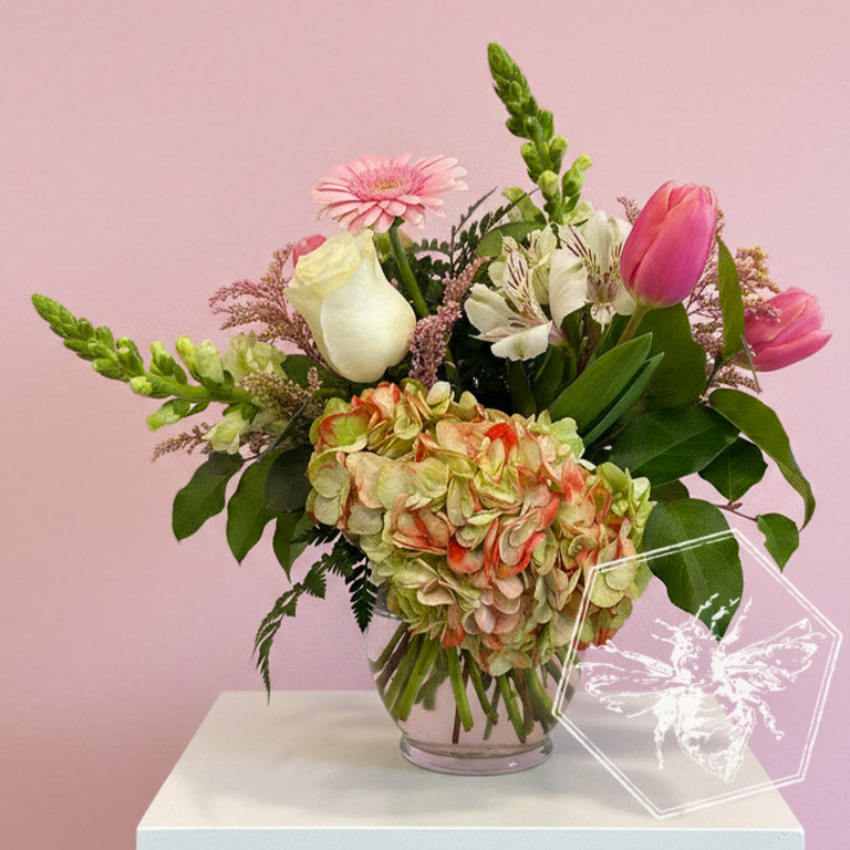 A traditional vase featuring white roses, lilies and reverent greens
