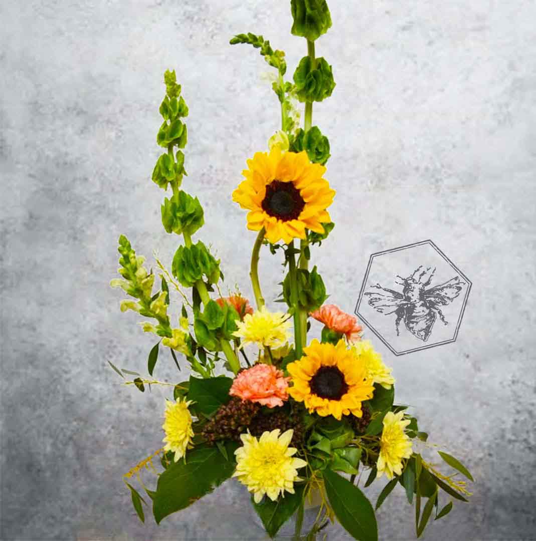 Luxurious modern arranged sunflowers featuring bells of Ireland, carnations and fresh complimentary greens 