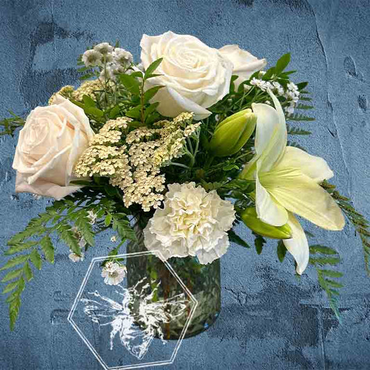 Bouquet of white flowers in a hexagonal vase on a textured blue background
