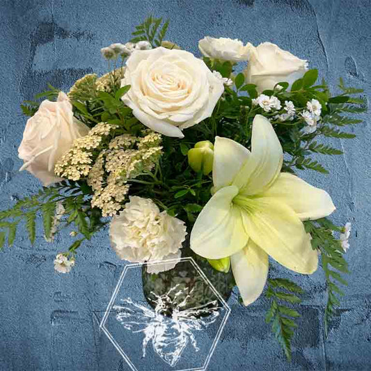 Vase full of white lilies and roses with complimentary  flowers on a textured blue background